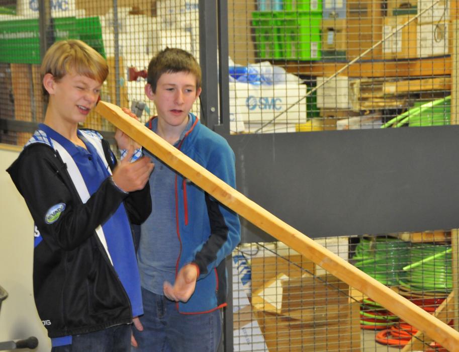 Halen Harrison, left, and Bennett Card check their piece of lumber for warping in their project to build a canoe.