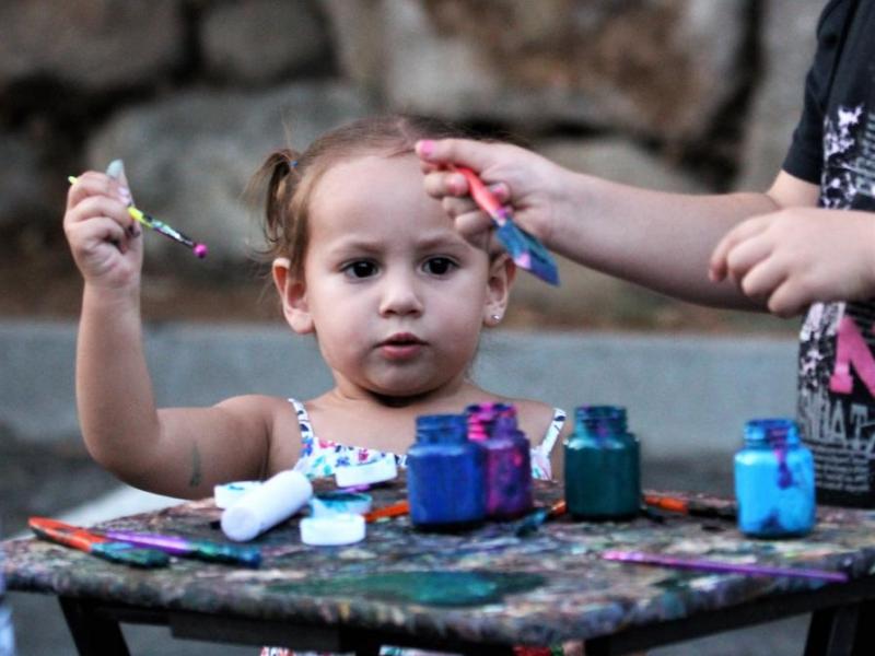 A small child paints on the oversized blank canvas during a Levitt AMP concert.