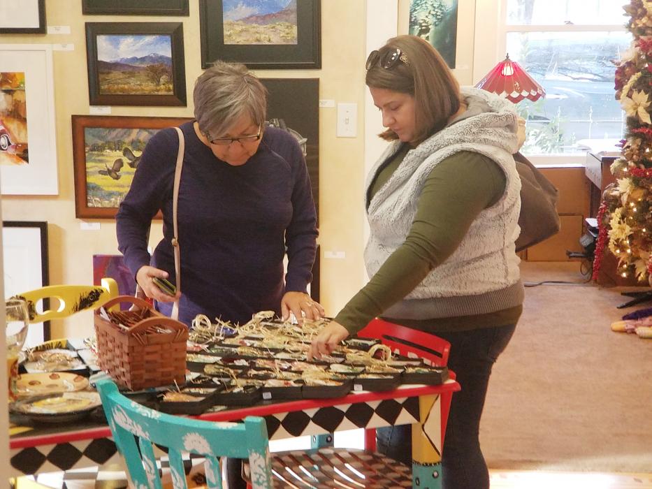 Photo by Brett Fisher. Shoppers browse jewelry inside Artsy Fartsy Art Gallery Saturday.