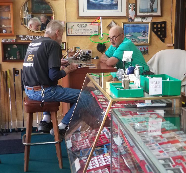 Photo by Brett Fisher. Dan Wilson, right, with a customer at Downtown Coin Saturday.