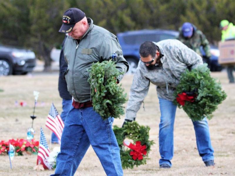 Volunteers carry wreaths to be laid at the graves of fallen military and veterans Saturday morning at Lone Mountain Cemetery.