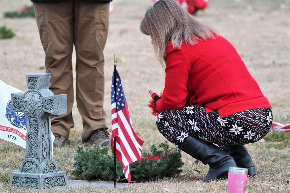 Family members regard a loved one buried at Lone Mountain Cemetery after laying a wreath at the grave.