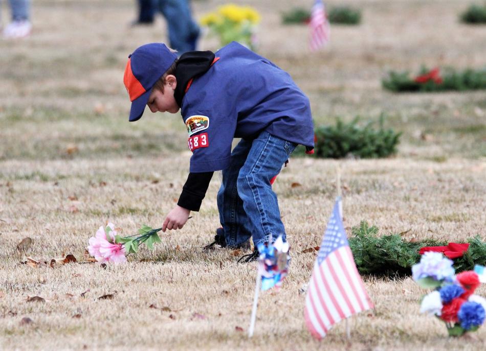 A Cub Scout lays flowers at a grave Saturday morning at Lone Mountain Cemetery.