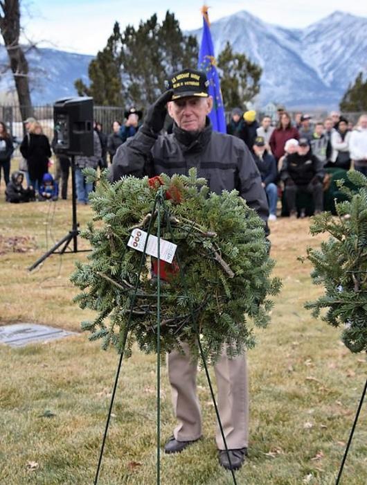 A Korean War veteran salutes a Christmas Wreath for fallen brethren.