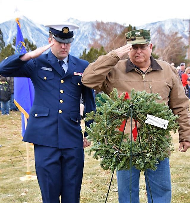 Active duty military and a veteran both salute the Christmas wreath for fallen brethren.
