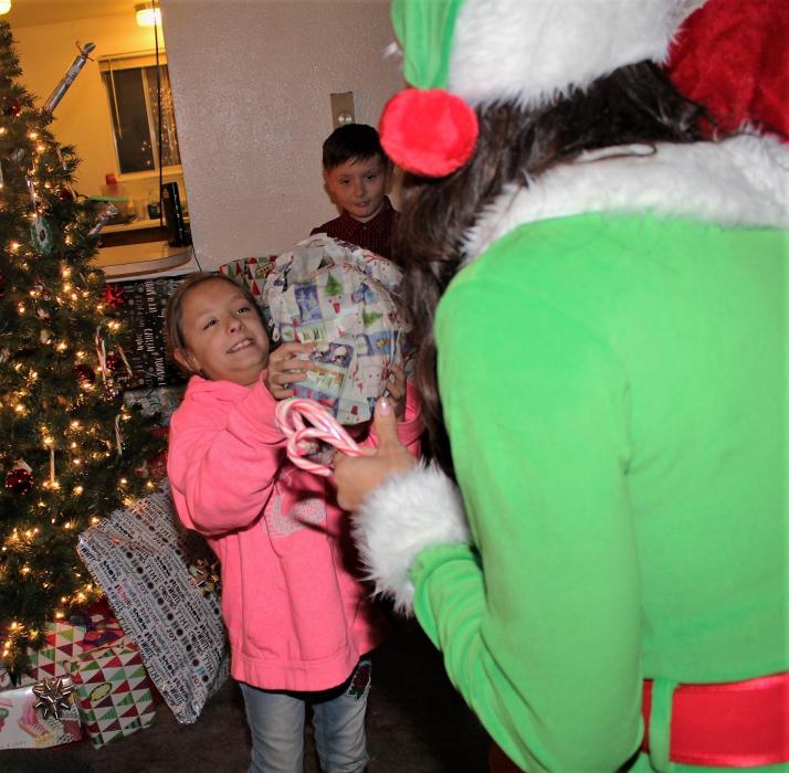 Santa hands a girl a gift Monday night in her home.