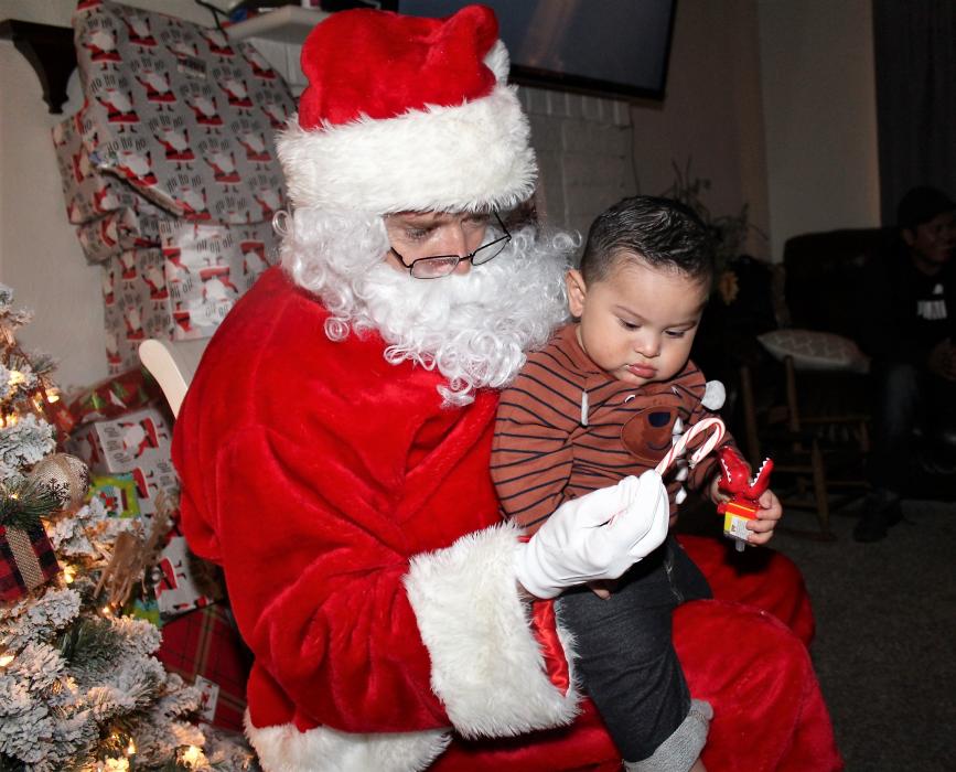 Santa Claus hands a candy cane to a small child on his lap Monday night.
