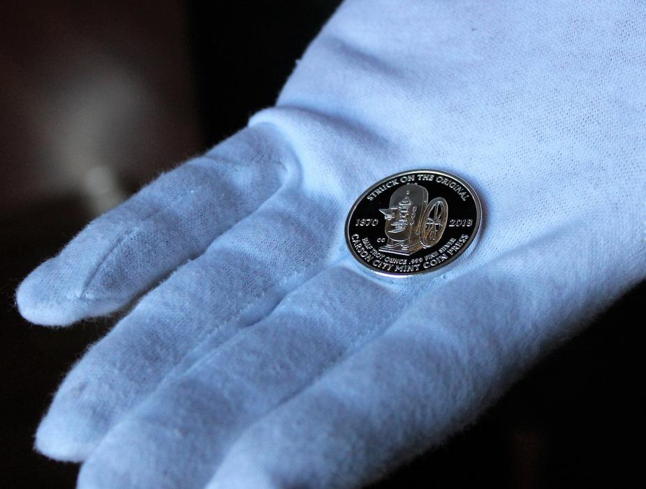 A Coin Press volunteer displays a freshly struck Abraham Curry Medallion Friday at the Nevada State Museum.