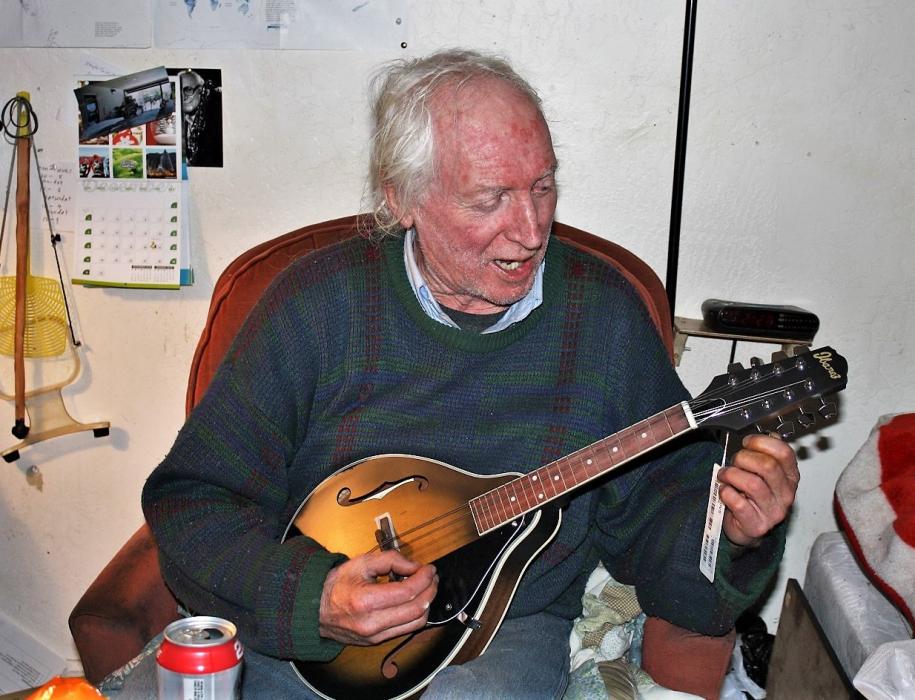 Meals on Wheels Carson City recipient Chris Laird delightedly plucks out a tune on his new mandolin, a gift from a donor.