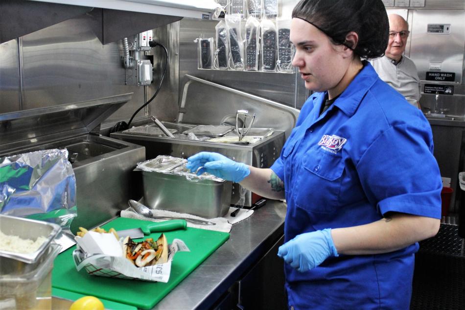 The kitchen manager puts the finishing touches on an Italian sausage sandwich.