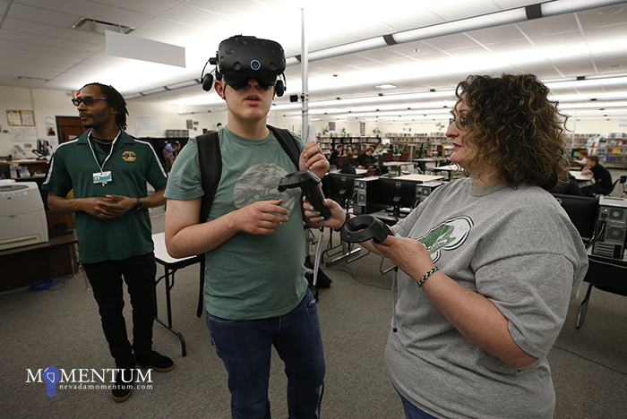Justin Worthy, left, and librarian Holly McPherson talk to senior Logan Evans as he works in a VR program in Fallon.