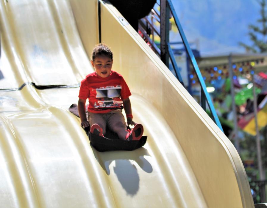 A girl slides down the giant slide at the Fourth of July Carnival in Mills Park.