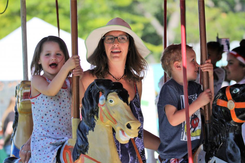 A family aboard the carousel at the Fourth of July Carnival in Mills Park.