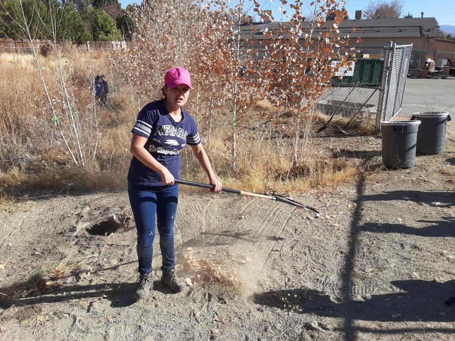 STEM teacher Katelyn Howard rakes up weeds.
