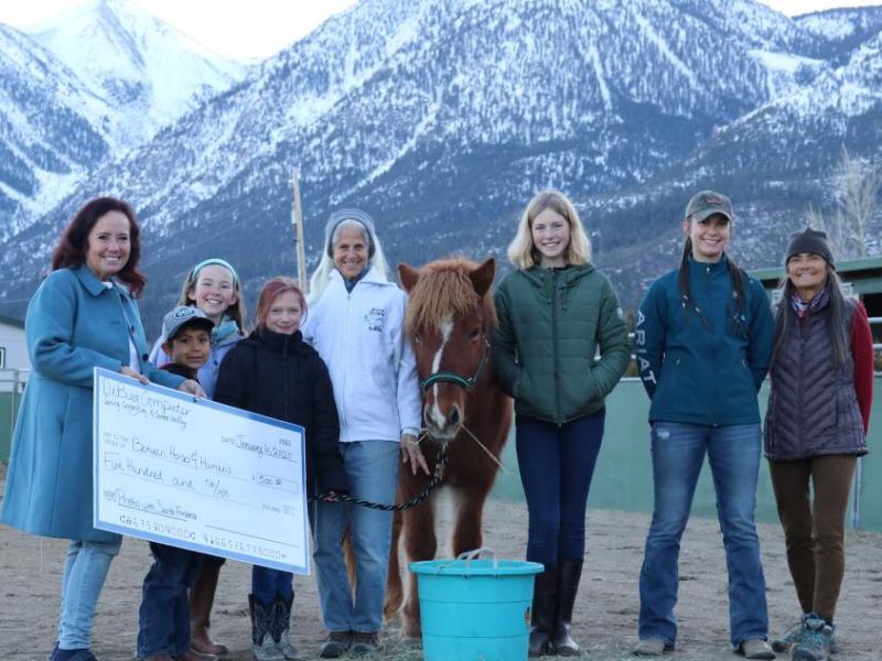 Debbie Barham (left), co-owner of DeBug Computer, presents a check for $500 to Between Horses and Humans.