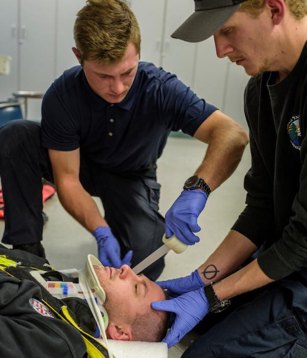 Trae Workman and Justin Bardling practice crisis health skills on Josh Wilcox during an Emergency Medical Services class.