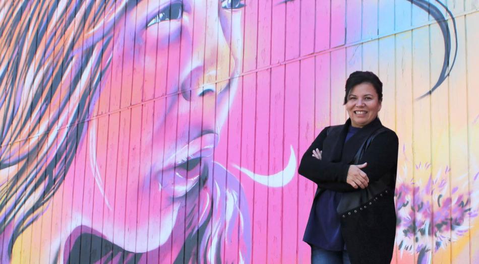 BAC Executive Director Gina Lopez stands in front of the Bryce Chisholm mural commissioned by the Downtown Business Association.
