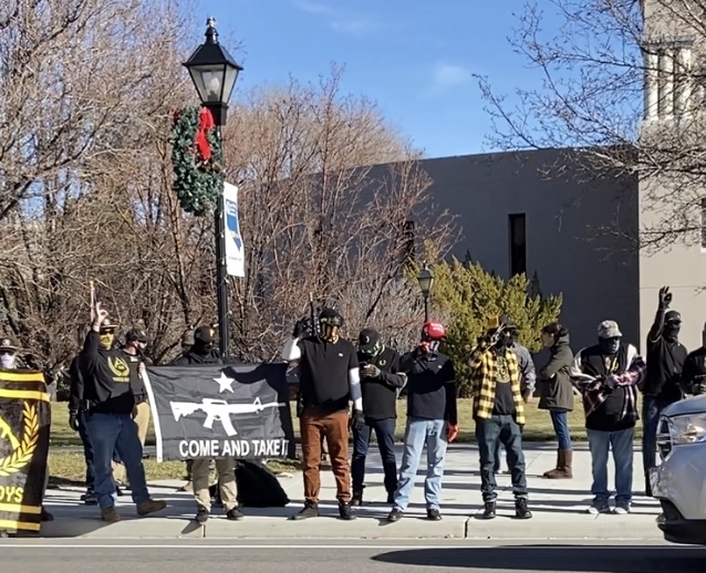 A group of Proud Boys flash 'White Power' hand signals at passing traffic