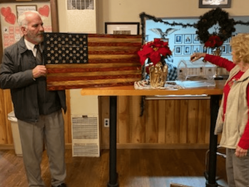 Exalted Ruler Jim Smolenski holds Wooden Flag as Uli Morgan draws raffle winning ticket.