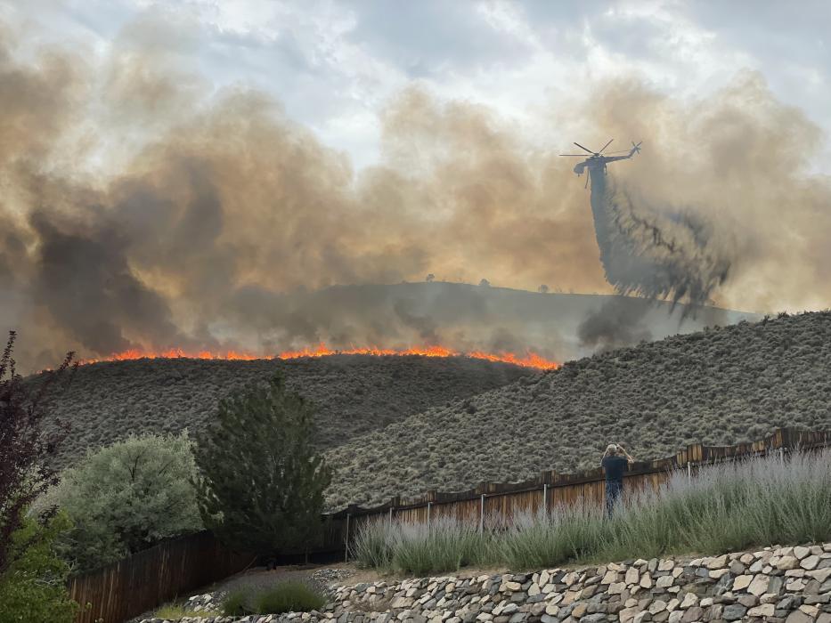A helicopter drops water on the Prison Hill fire near residential homes