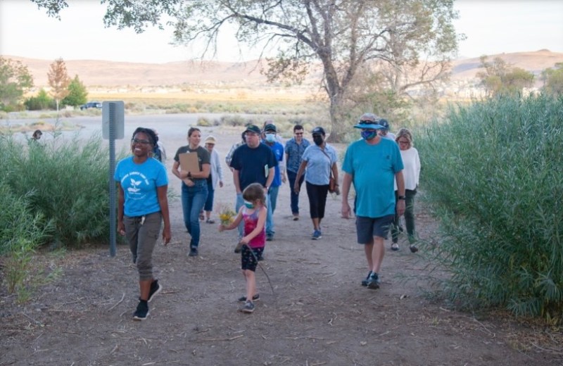 A small group of people are gathered outdoors on a hiking trail.