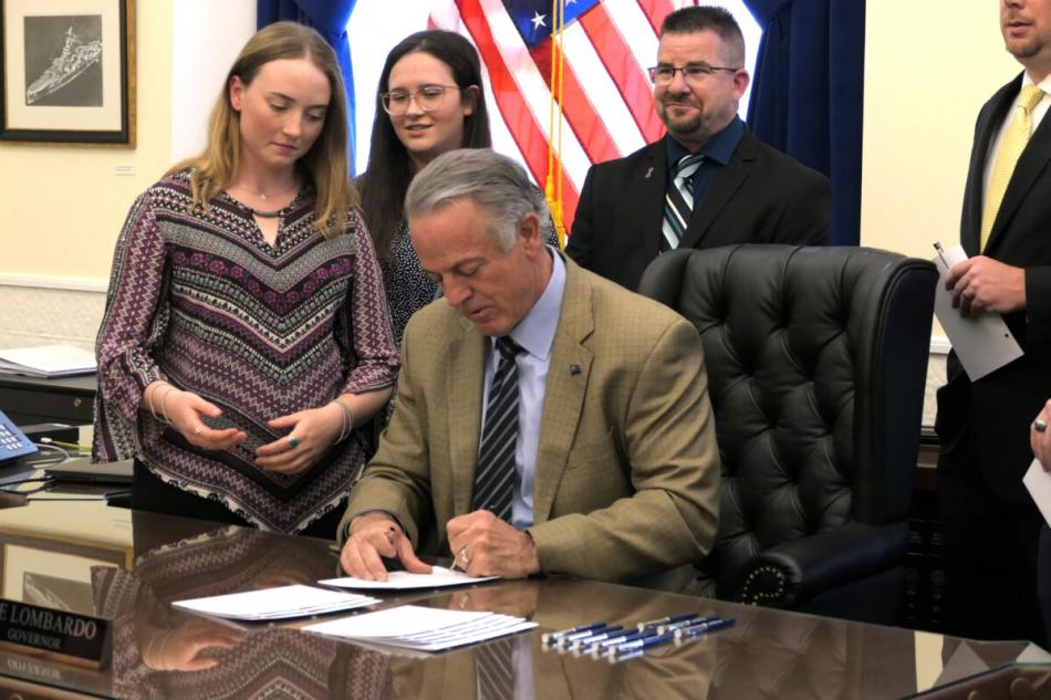 tella Thornton (left) watches as Gov. Joe Lombardo (seated) signs SB80 during the bill's ceremonial signing in Carson City.