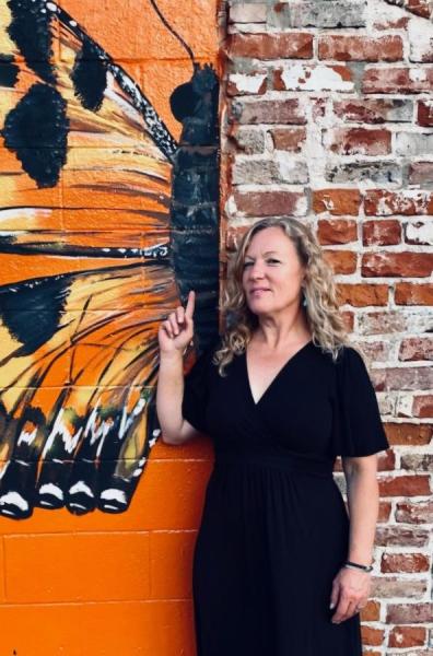 Dr. Anna Camp stands next to a mural