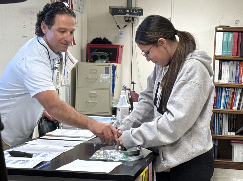 Chemistry teacher Ty McMillen assists a student in opening her Yondr pouch