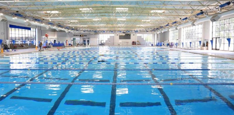 A photo of an indoor blue pool with a number of horizontal lap lanes across the water, framed by large windows.